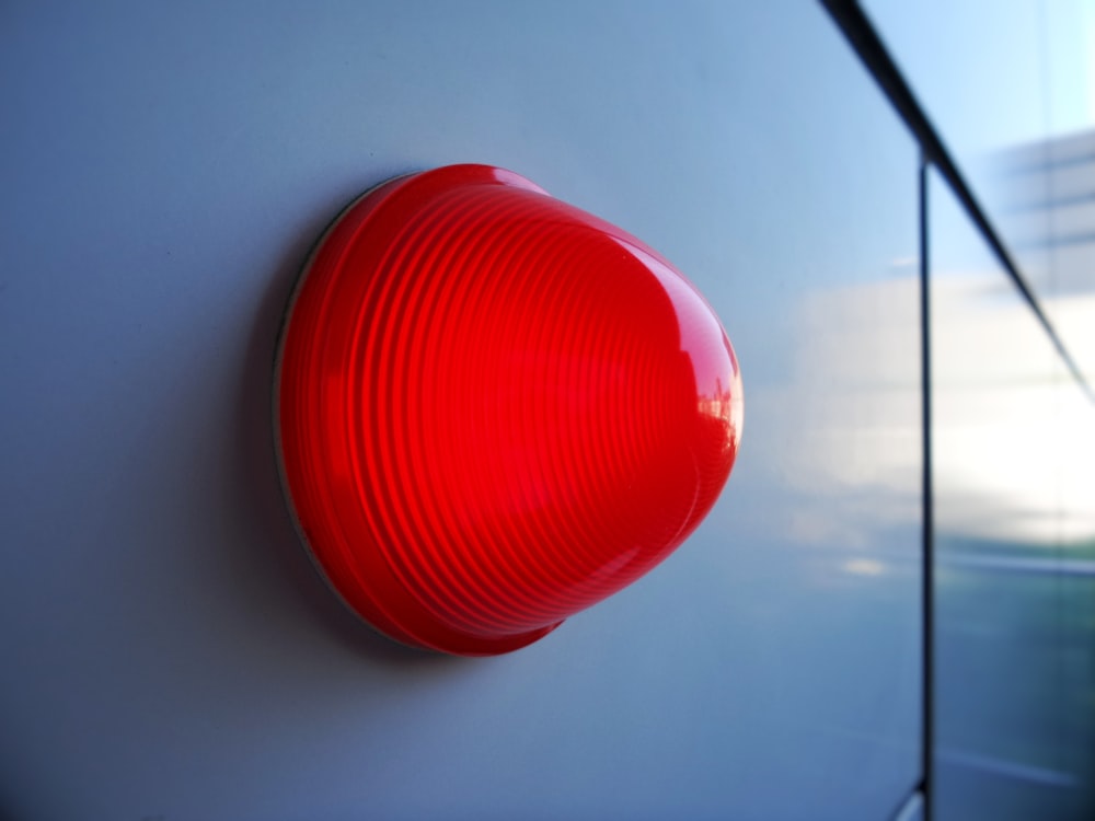 a close up of a red light on a white wall