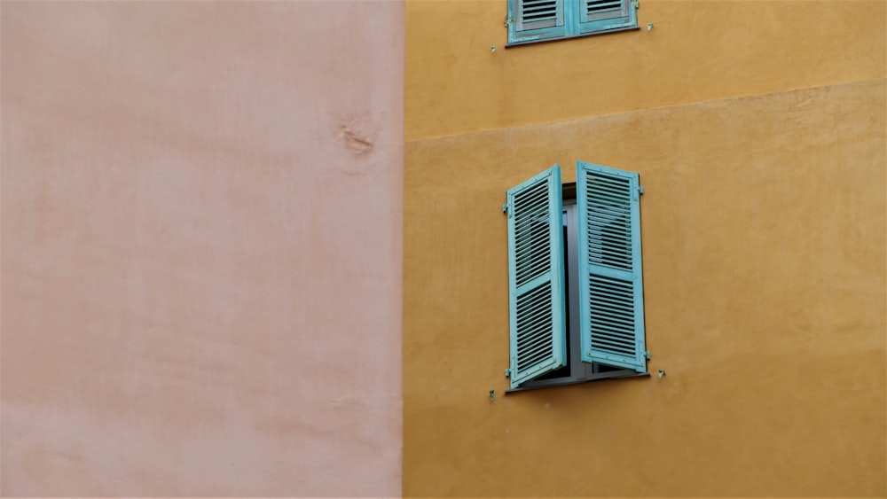 two windows with blue shutters on the side of a building