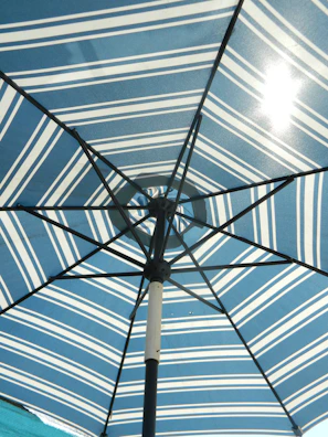 Close-up of a durable fabric parasol casting a gentle shadow on a sunlit patio.