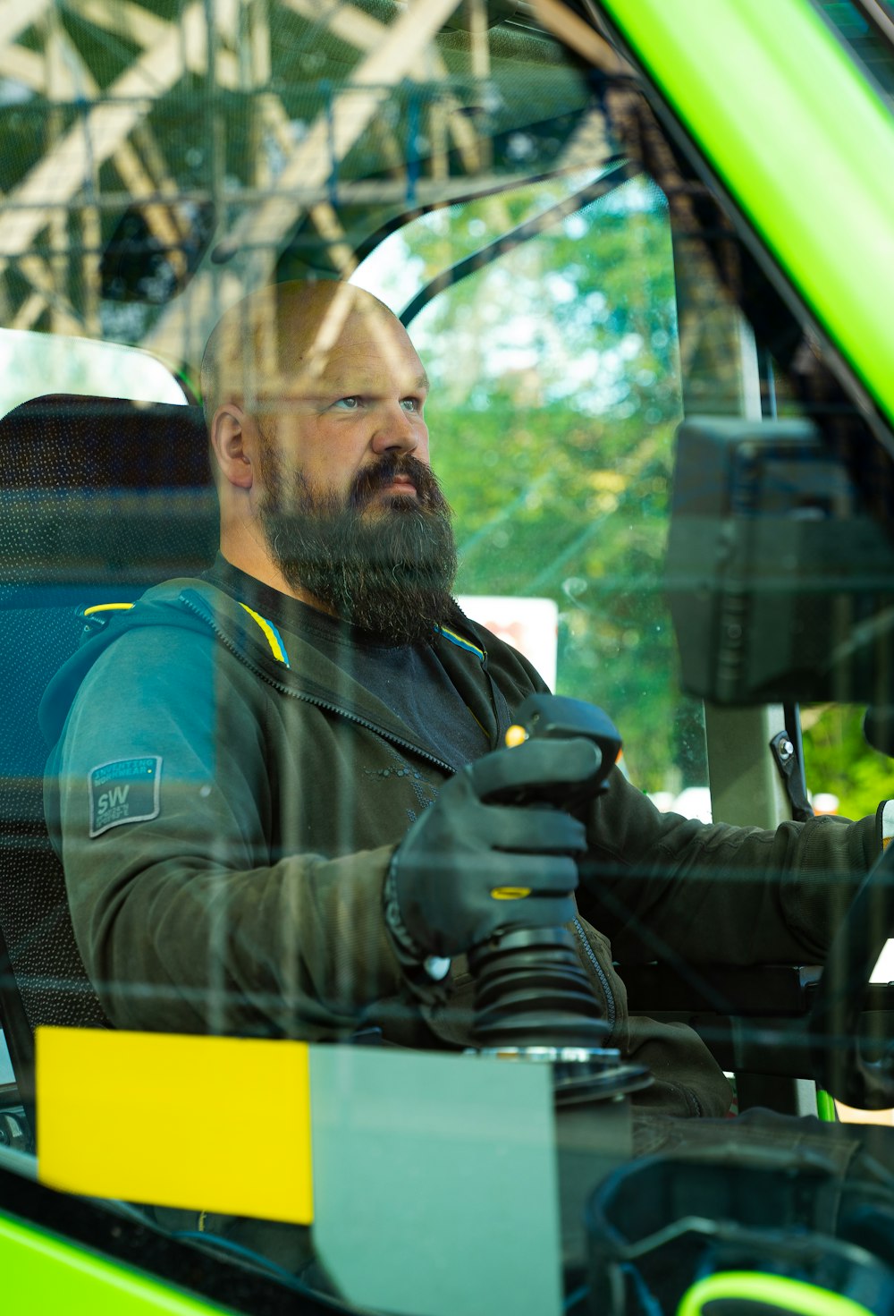 a man sitting in a green vehicle with his hand on the steering wheel