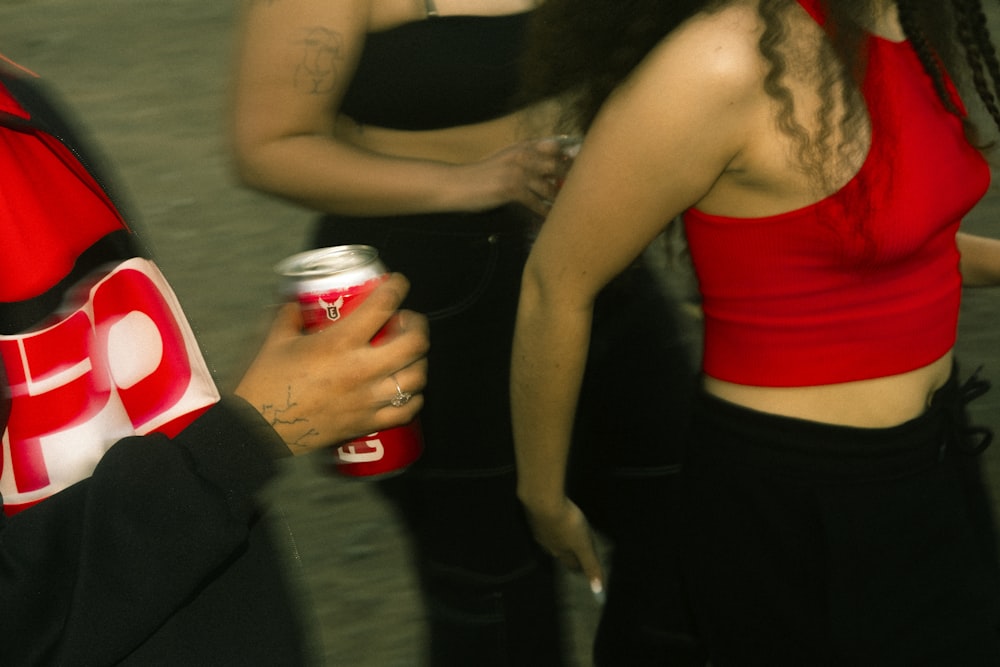 a woman in a red top holding a can of soda
