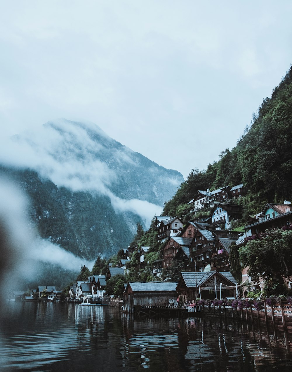 a lake with houses and mountains in the background