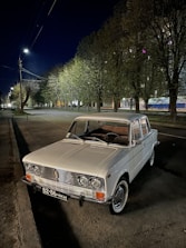 A well-kept older car parked on a quiet village street under soft daylight.