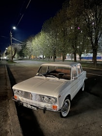 A well-kept older car parked on a quiet village street under soft daylight.