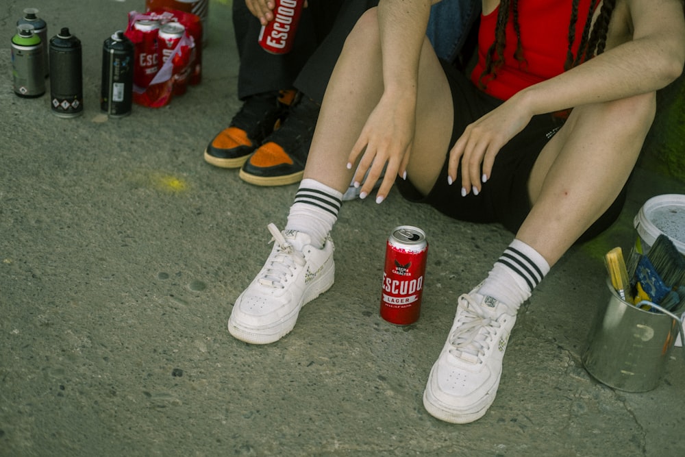 a woman sitting on the ground next to a can of soda