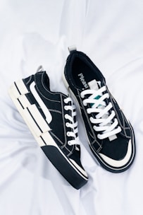 a pair of black and white sneakers on a white sheet