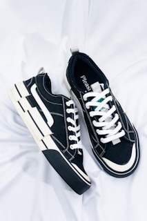 a pair of black and white sneakers on a white sheet