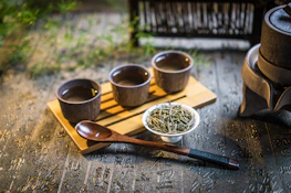 a wooden tray topped with three cups filled with green tea