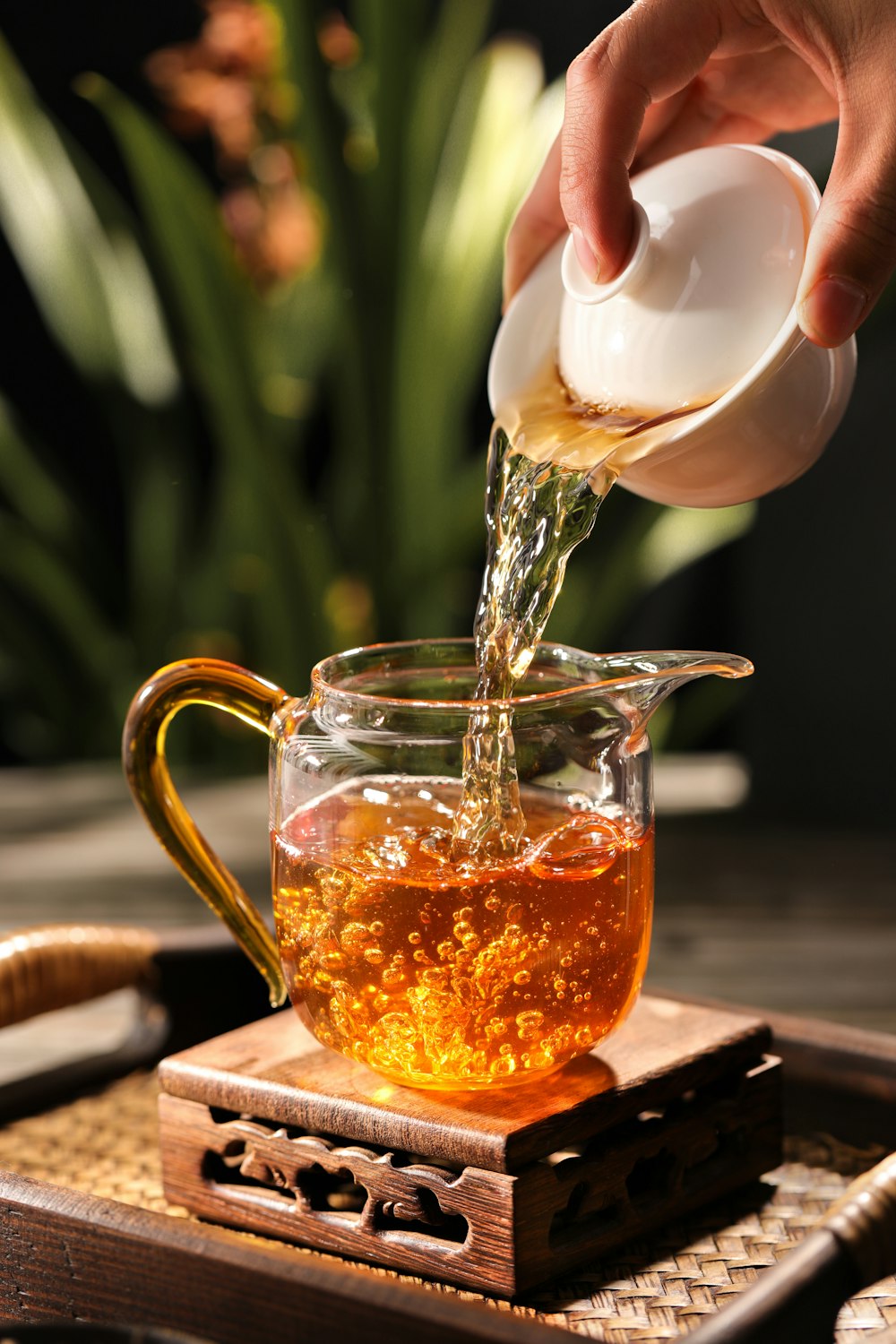 a person pouring tea into a glass teapot