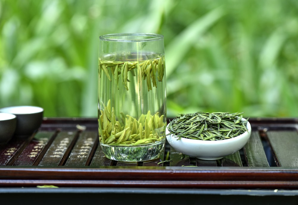 a glass of green tea next to a bowl of green tea