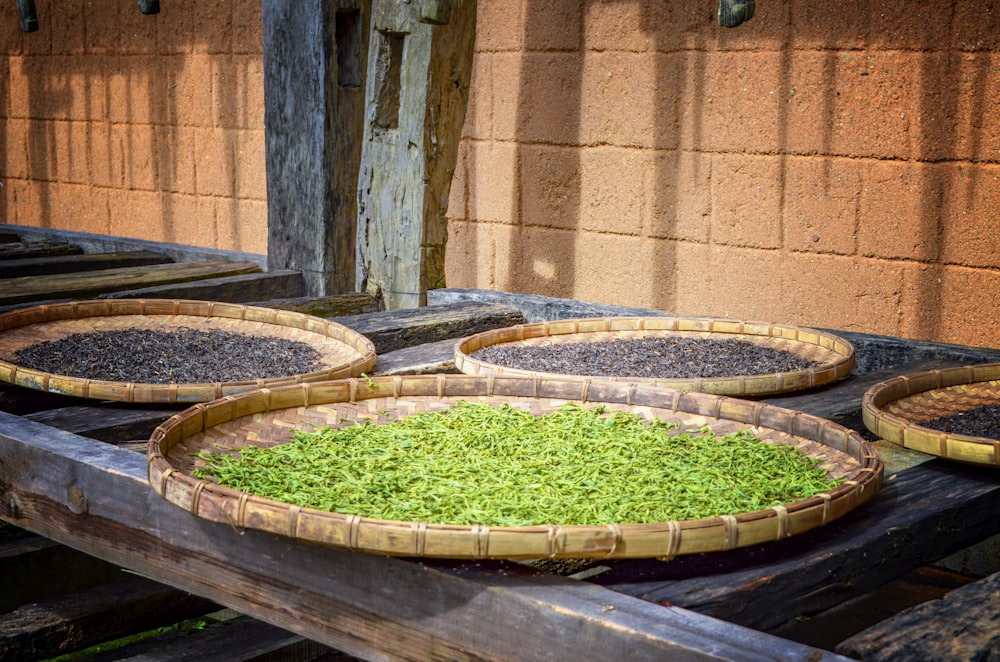 a wooden table topped with bowls filled with green plants