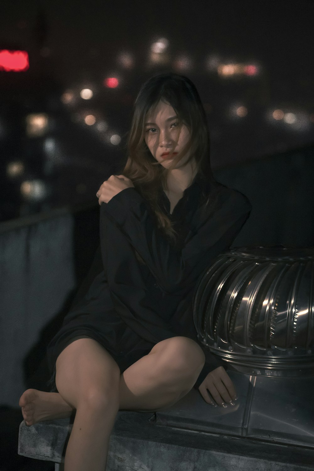 a woman in a black dress sitting on a ledge