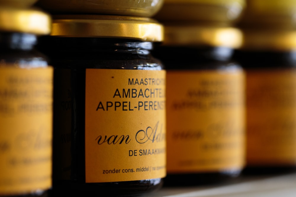 a row of jars filled with jam sitting on top of a shelf