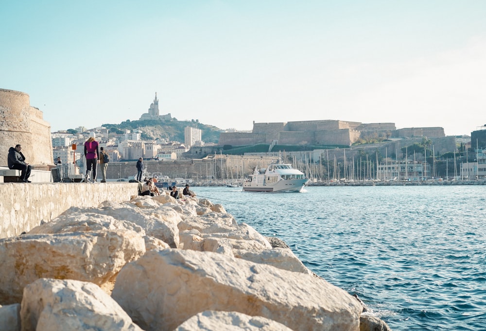 a group of people sitting on a wall next to a body of water