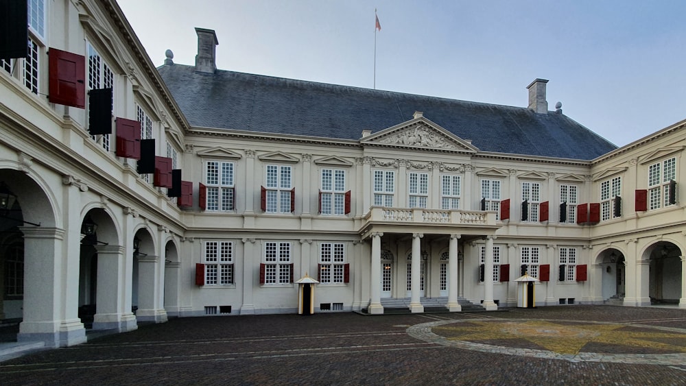 a large white building with red shutters on the windows