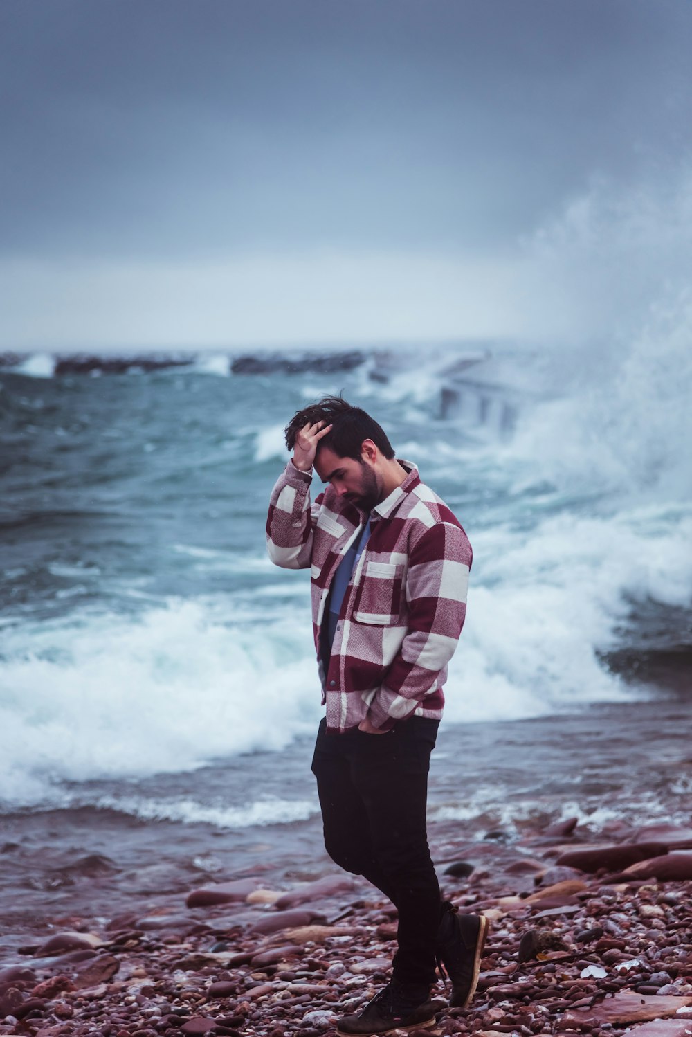 a man standing on a rocky beach next to the ocean