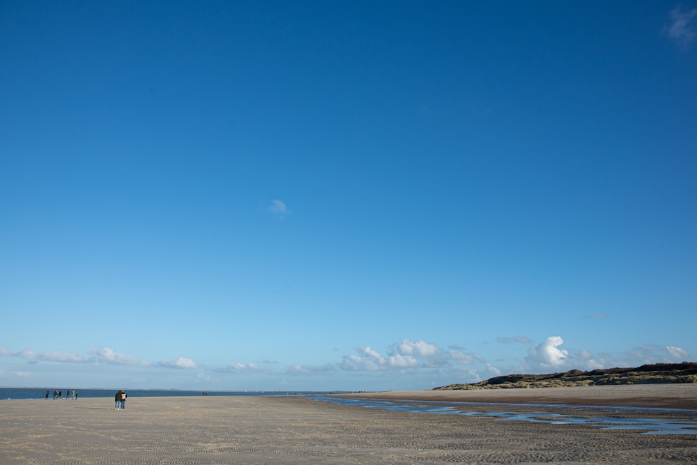 a couple of people standing on top of a sandy beach