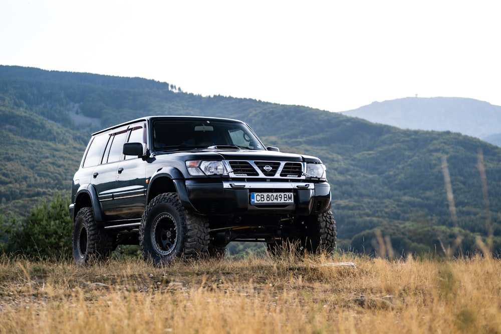 a black suv parked in a field with mountains in the background