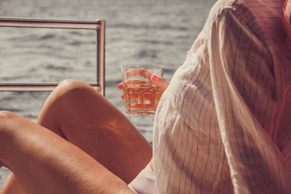 a woman sitting on a dock holding a glass of water