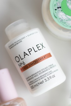 a bottle of olaplex next to a container of lotion