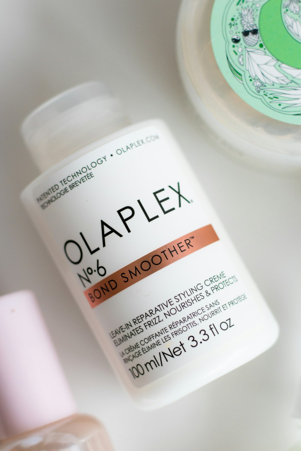 a bottle of olaplex next to a container of lotion