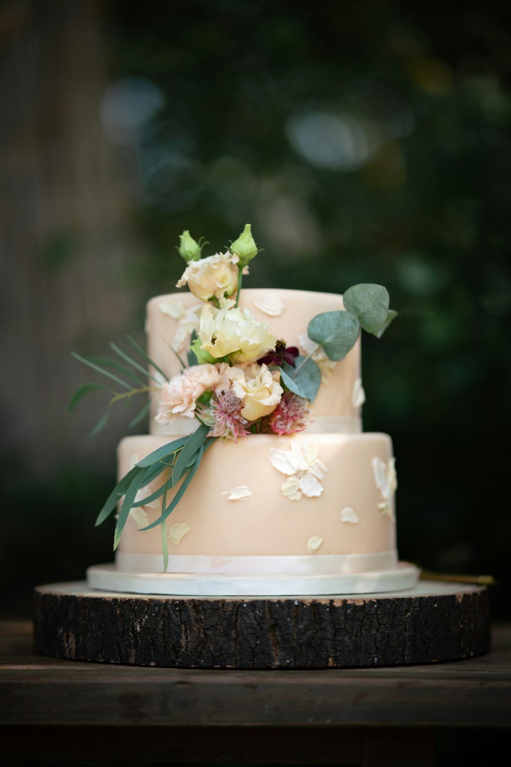 a three tiered wedding cake with flowers on top