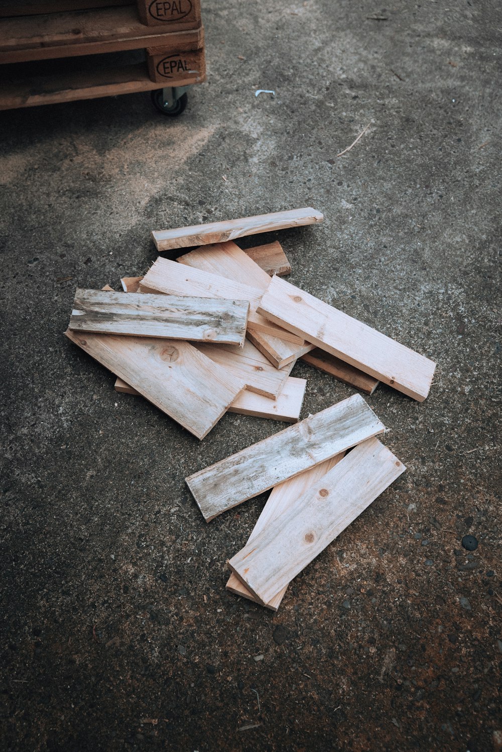 a pile of wood sitting on top of a cement ground