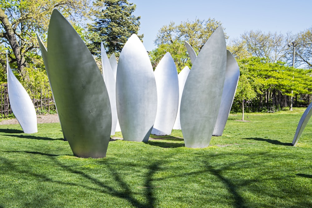 a group of white sculptures sitting on top of a lush green field