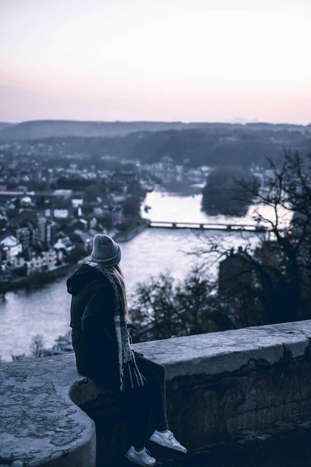 a person sitting on a ledge overlooking a river