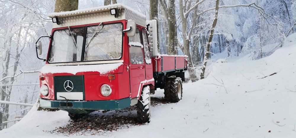 a red truck parked on top of a snow covered forest