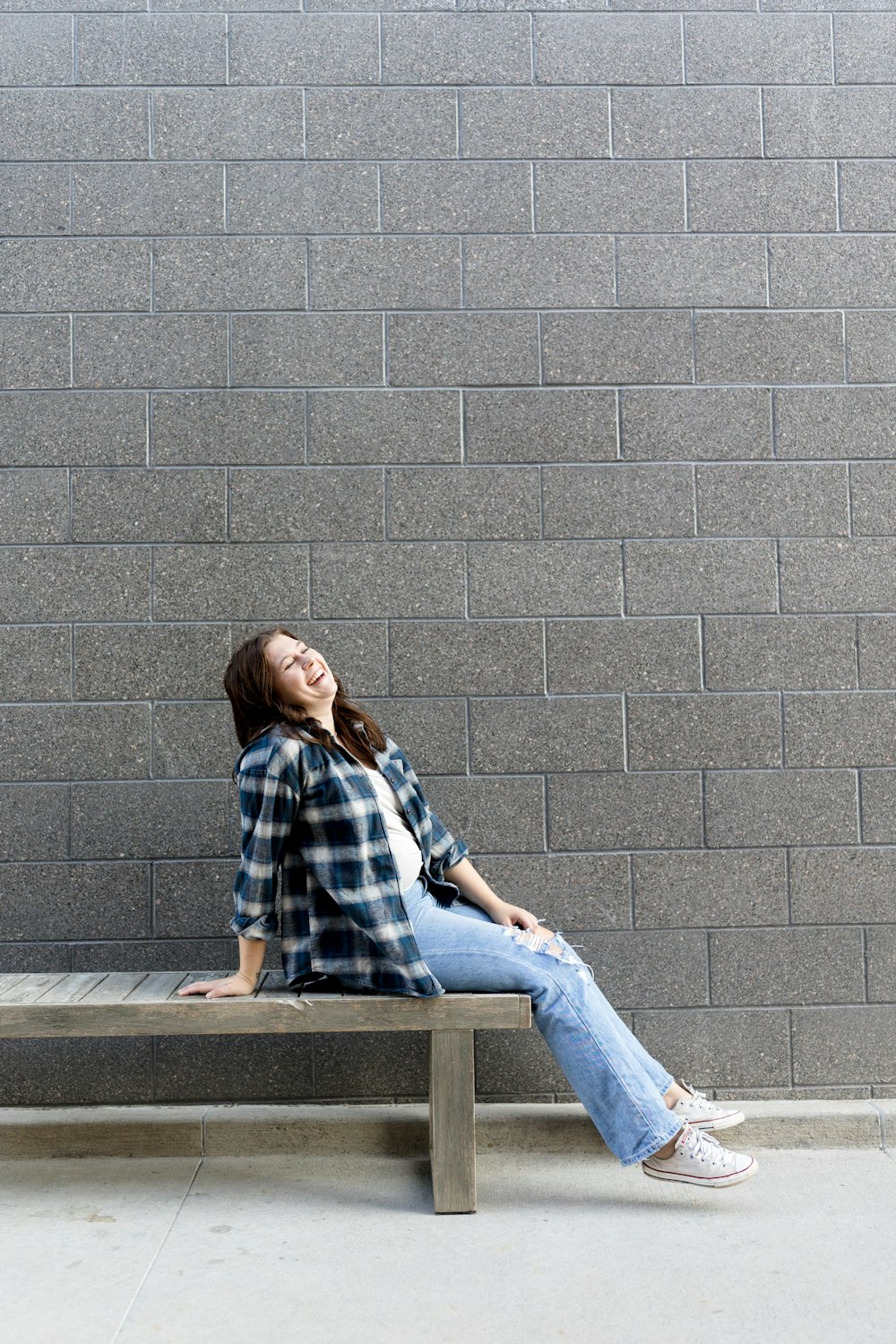 Eine Frau sitzt auf einer Bank vor einer Ziegelmauer