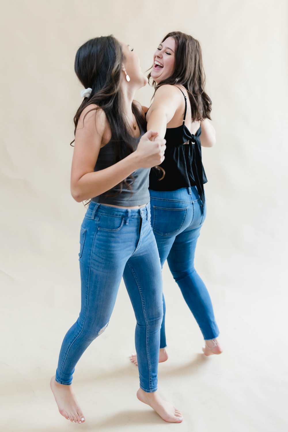 two women standing next to each other in jeans