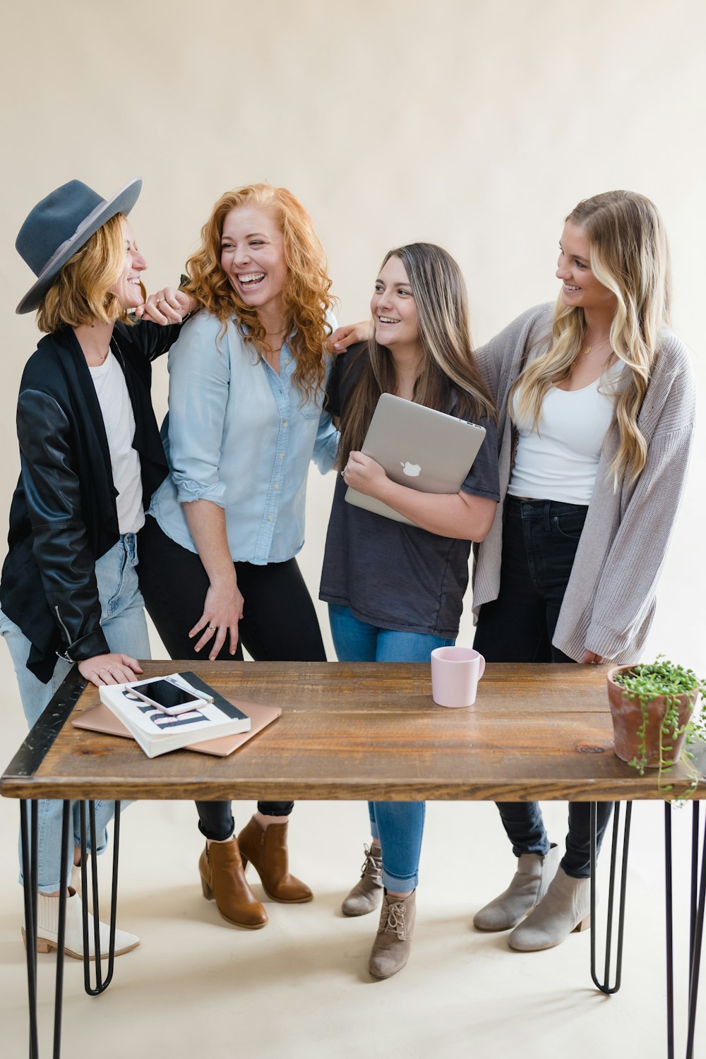 um grupo de mulheres em pé ao redor de uma mesa de madeira