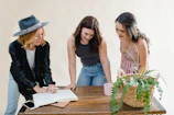Women gathered around a wooden table, deeply focused on painting and crafting