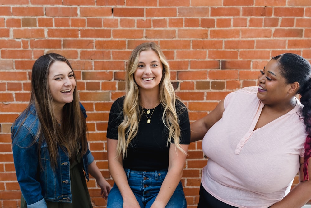 a group of women standing next to a brick wall