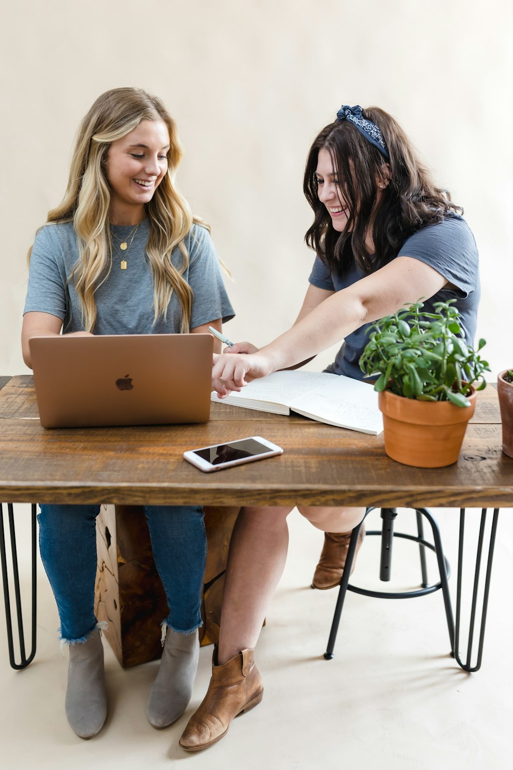 two women sitting at a table working on a laptop