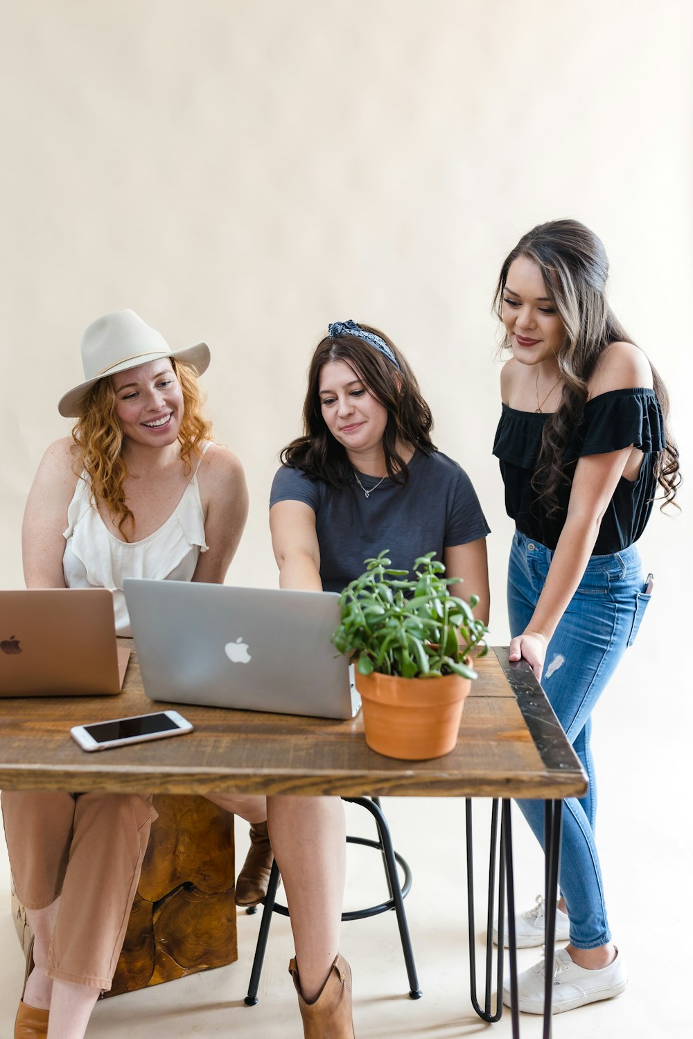 three women sitting at a table looking at a laptop