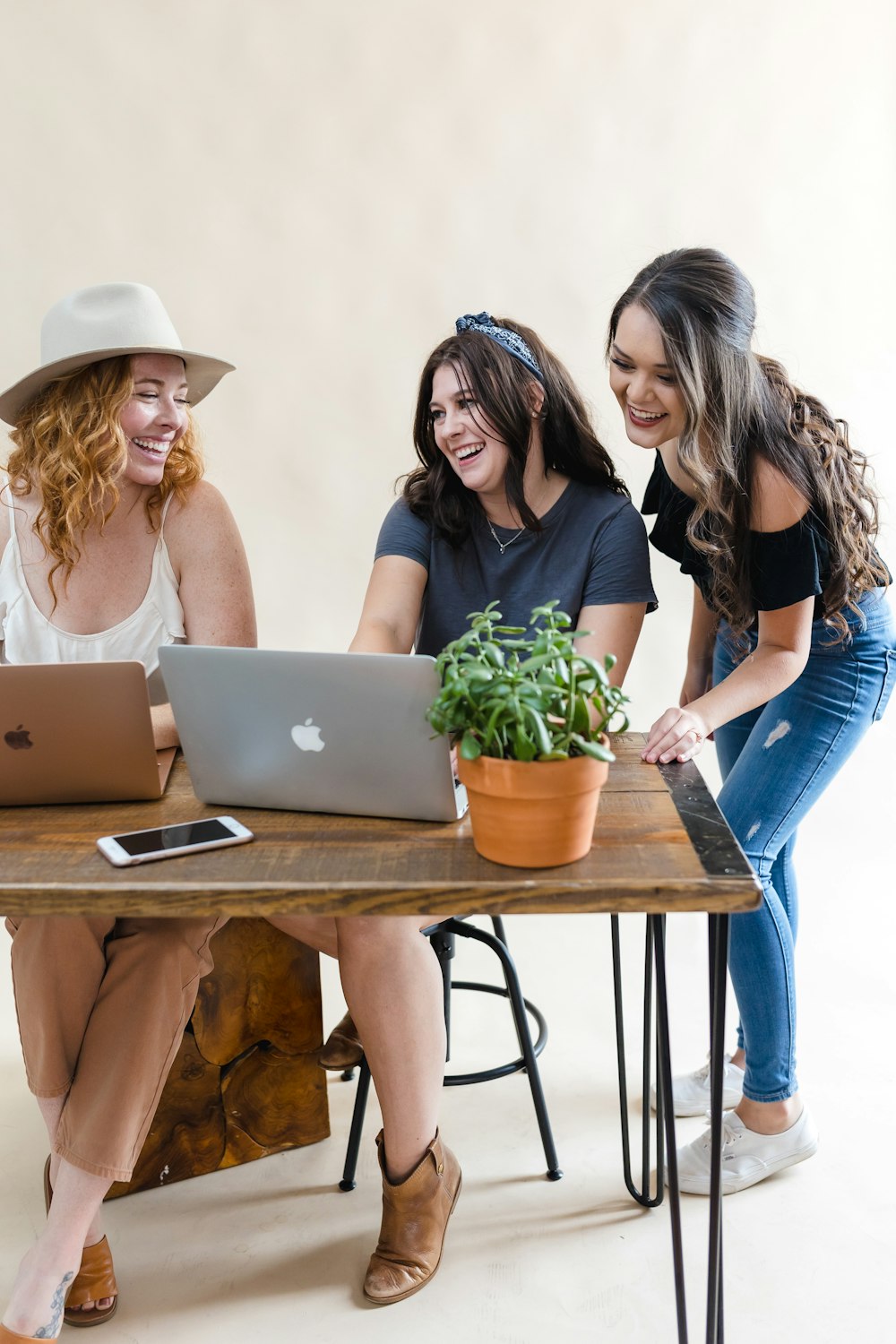 three women sitting at a table with a laptop