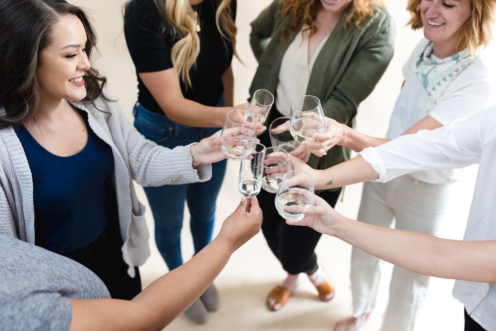 a group of women standing around each other holding wine glasses