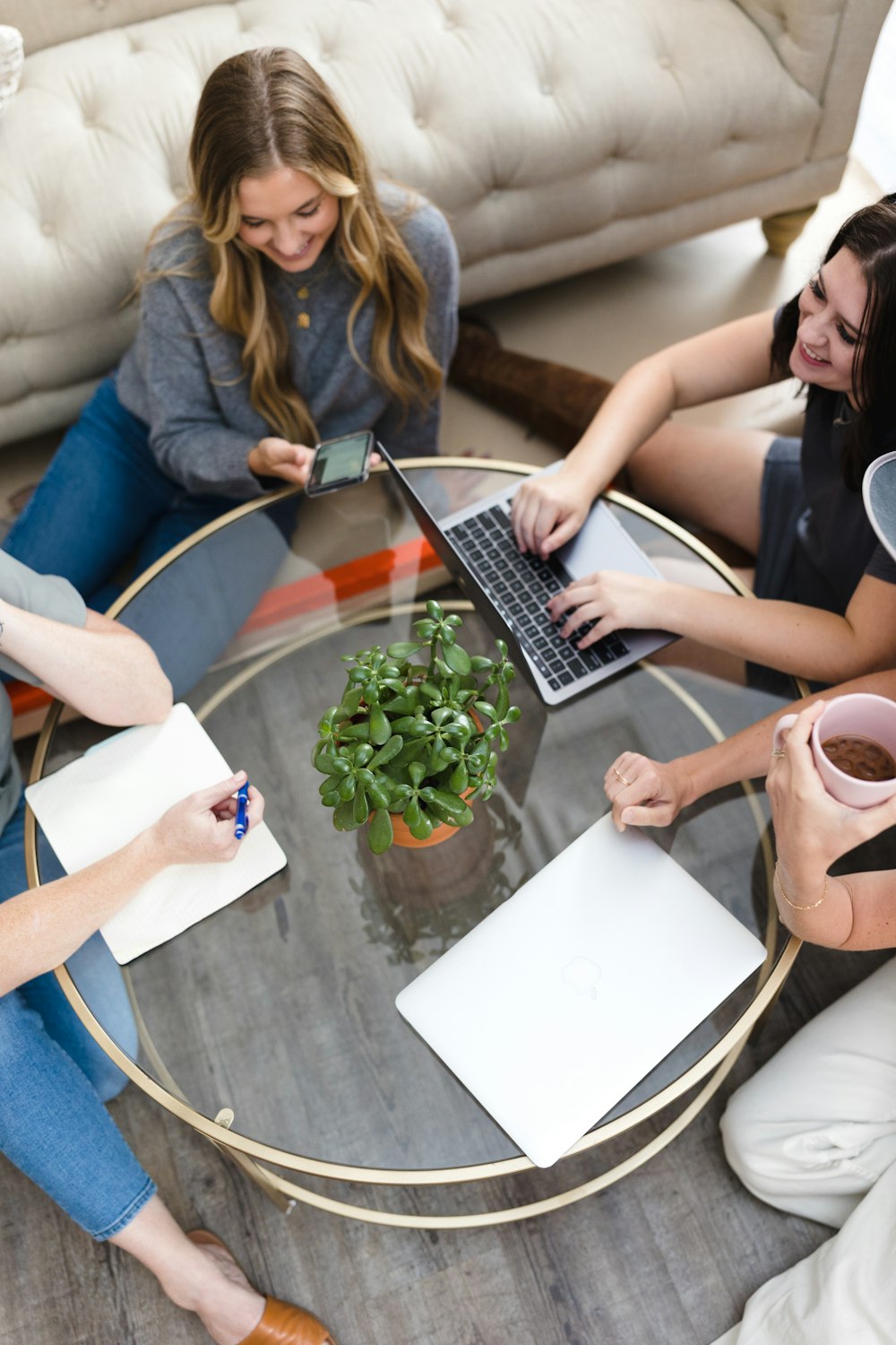 Un grupo de mujeres sentadas alrededor de una mesa de cristal