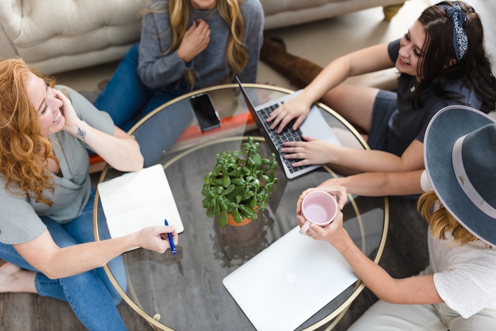 a group of women sitting around a table working on laptops