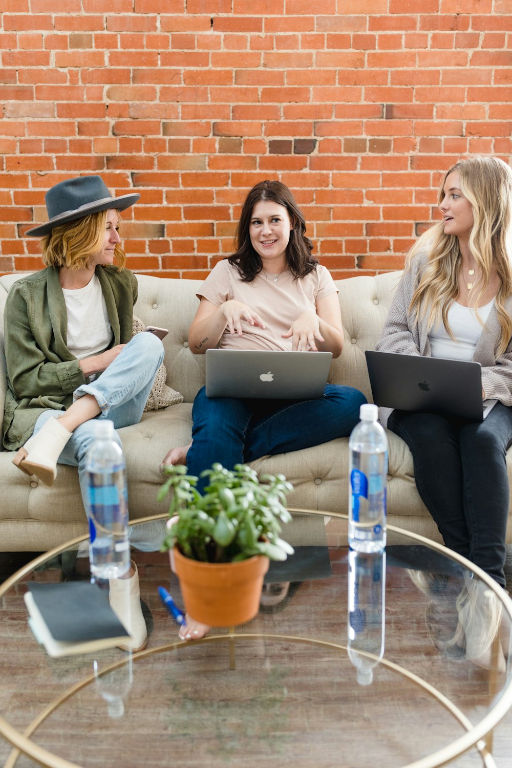 three women sitting on a couch with laptops