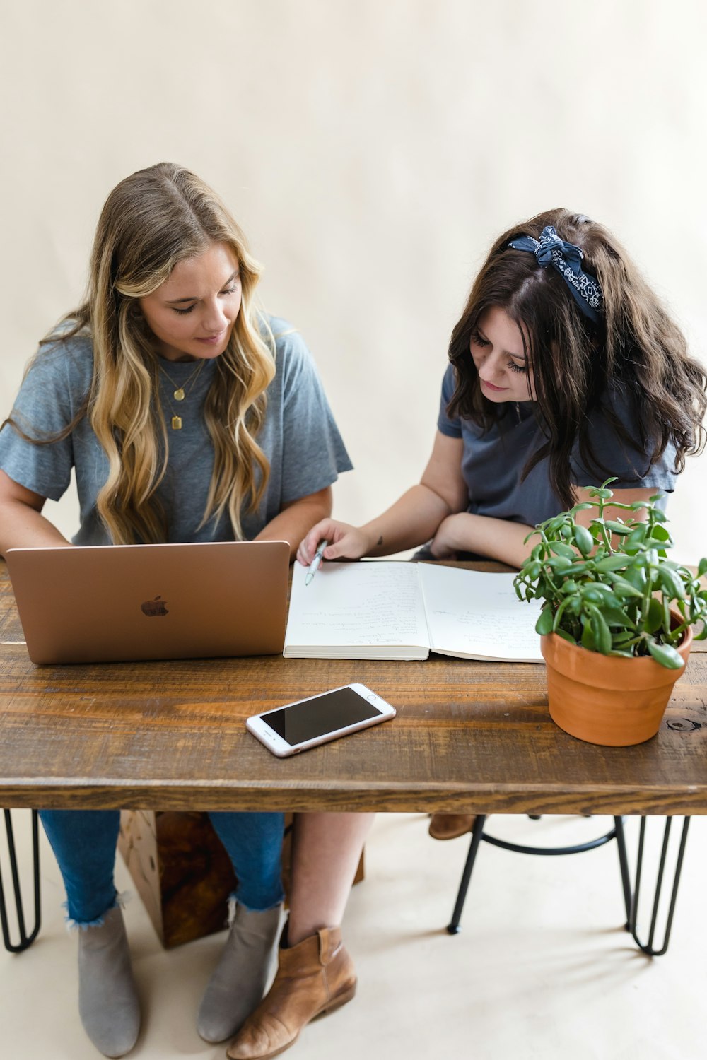two girls sitting at a table with a laptop