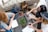 A diverse group of people happily using laptops and smartphones in a cozy indoor setting.