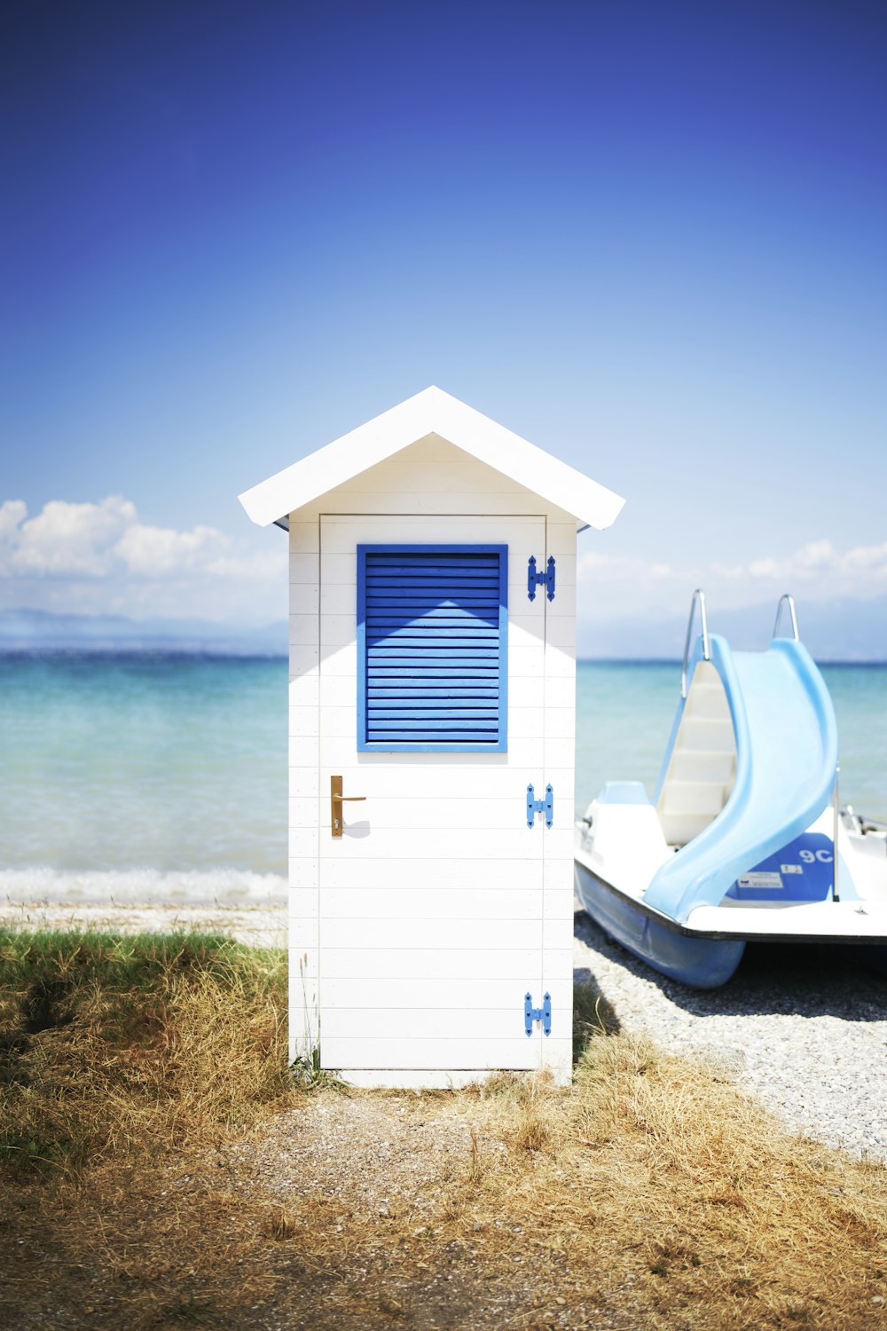 a small white building with a slide next to the ocean