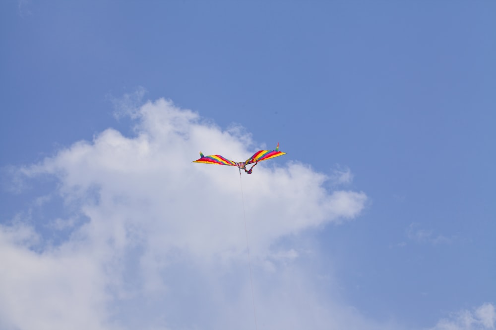 a colorful kite flying through a blue cloudy sky