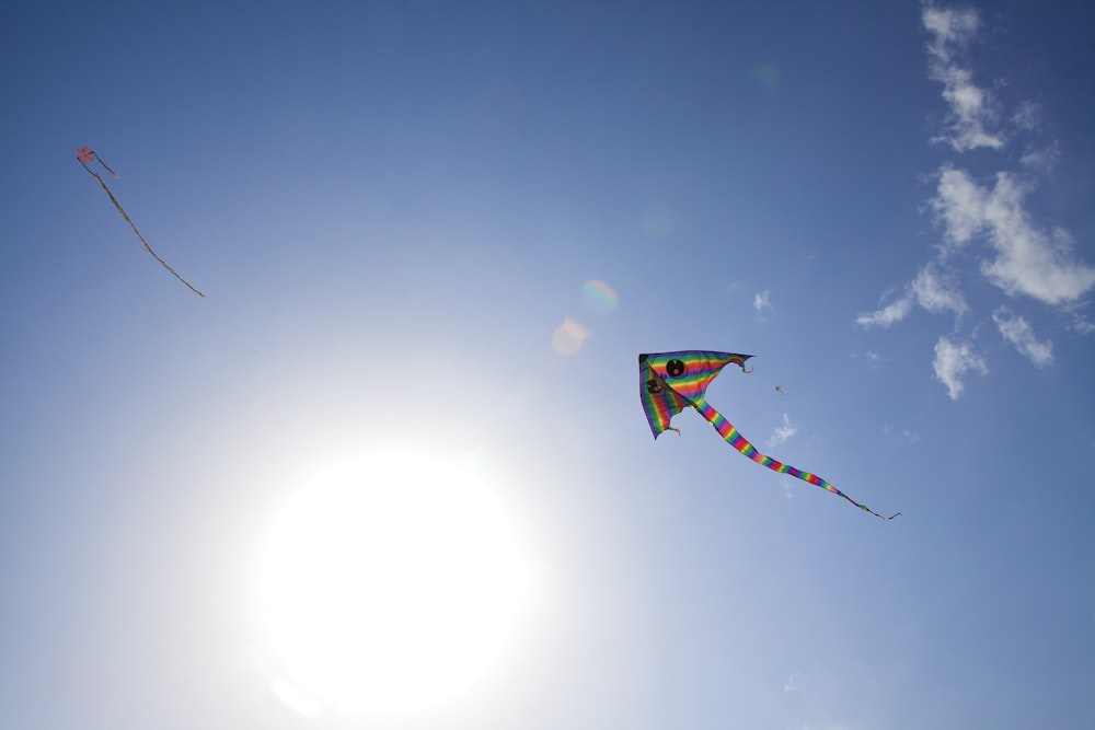 two kites flying in the sky on a sunny day