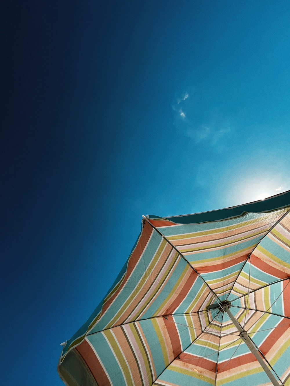 a striped umbrella with a blue sky in the background