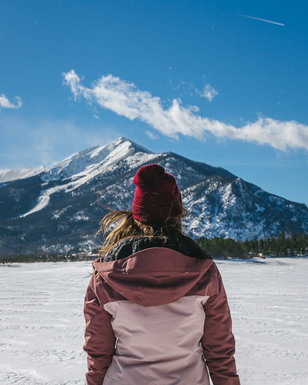 a woman standing in the snow with a mountain in the background