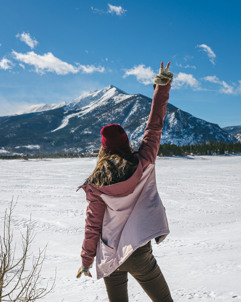 a woman standing in the snow with her arms in the air